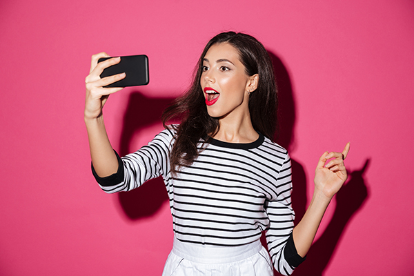 influenserka koja pravi selfie ispred ružičastog zida