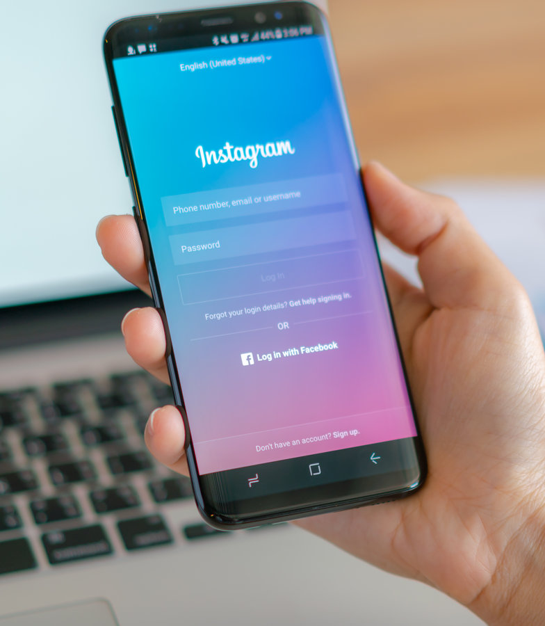 prikaz facebook aplikacije na telefonu i laptopu u pozadini