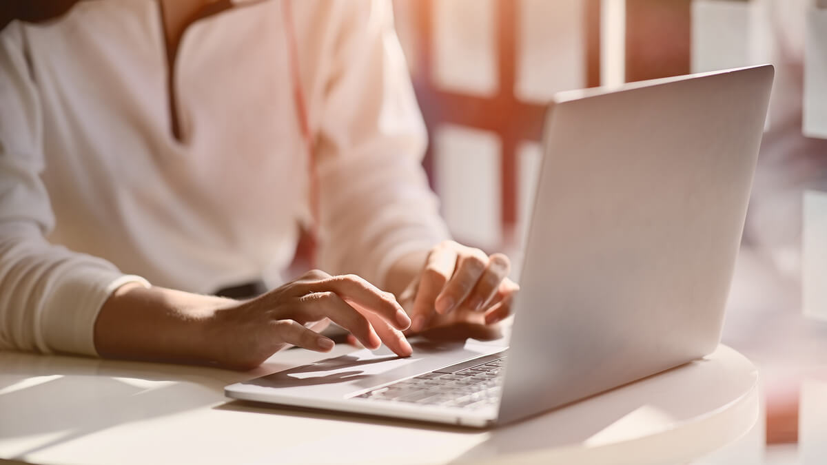 a woman typing on a laptop in a sunlit room